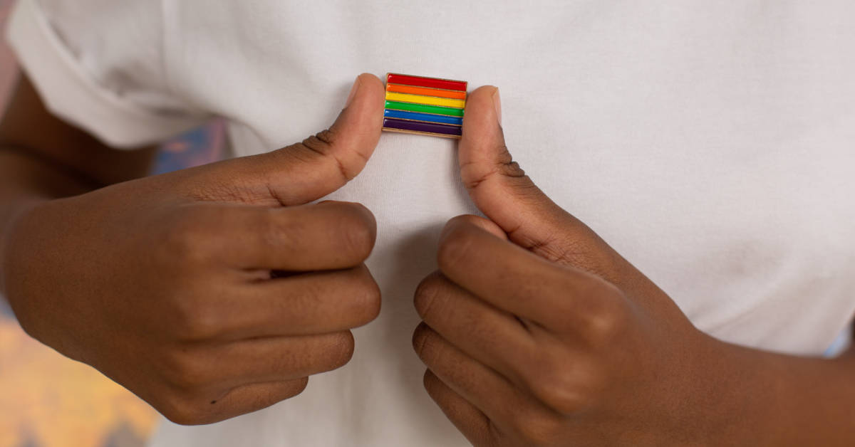 A photo of a person wearing a LGBTQ+ Pride pin badge